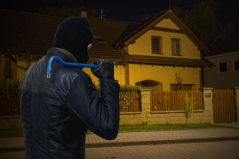 Einbrecher steht vor dem Haus bei Nacht